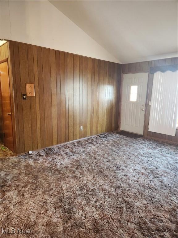 interior space with lofted ceiling and wood walls