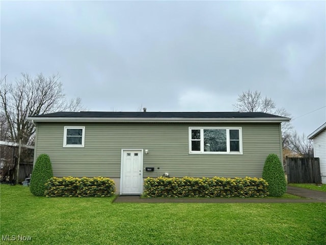 rear view of property featuring a yard and fence