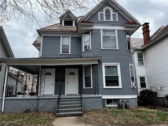 victorian house featuring covered porch and cooling unit