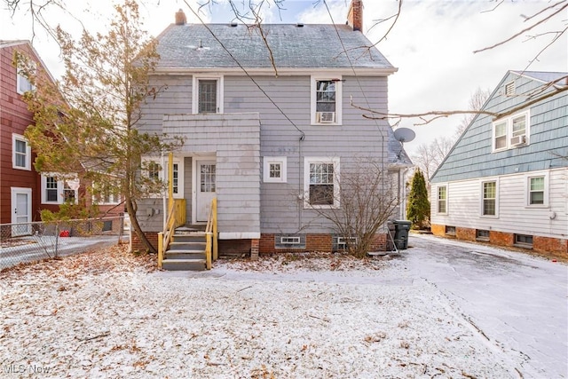 snow covered house with a chimney and fence