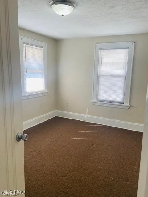 empty room with dark colored carpet and baseboards