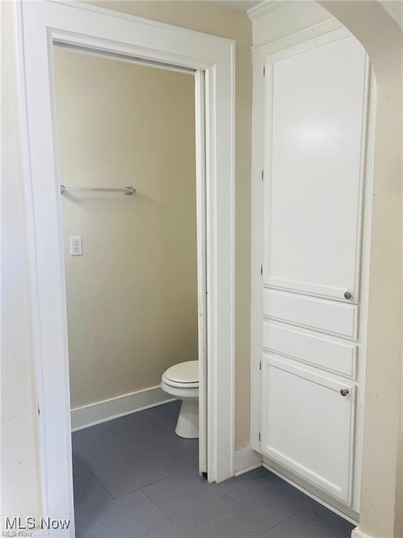 bathroom featuring toilet, tile patterned flooring, and baseboards