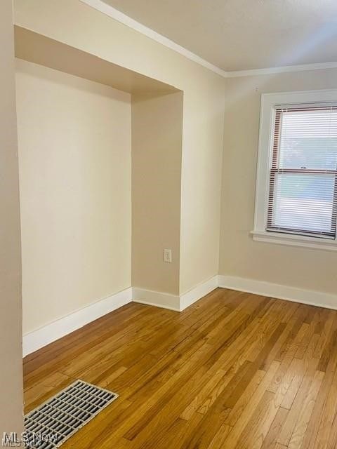 spare room featuring ornamental molding, wood finished floors, and baseboards