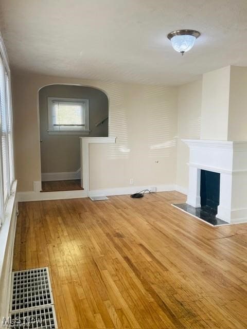 unfurnished living room featuring a fireplace, baseboards, and hardwood / wood-style floors