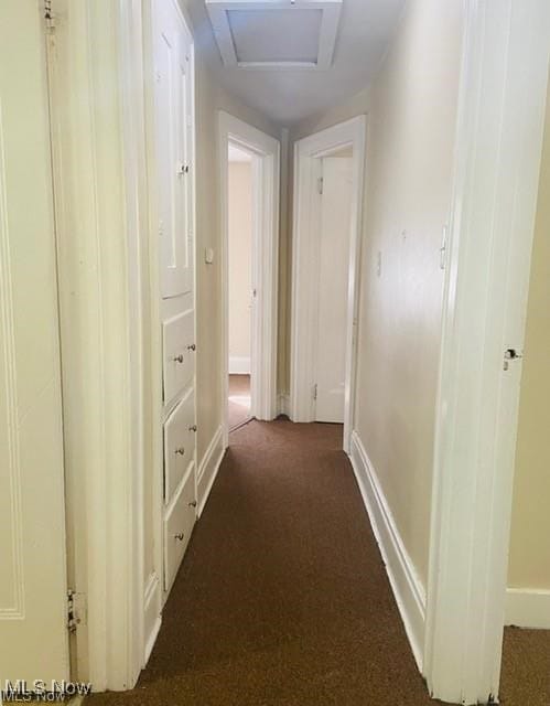 hallway with attic access, carpet, and baseboards