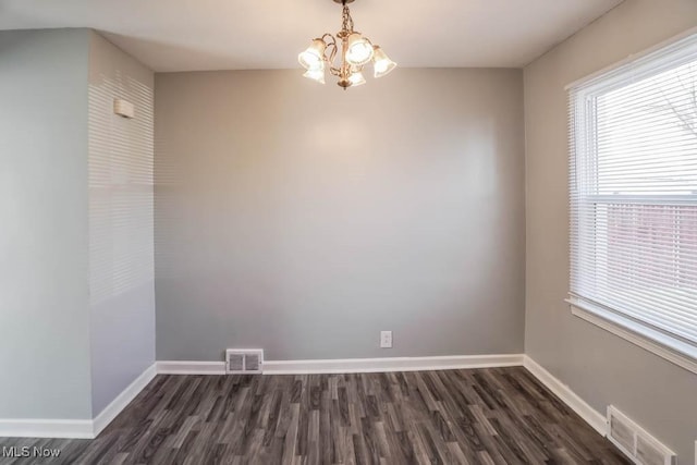 spare room featuring a chandelier, visible vents, dark wood finished floors, and baseboards