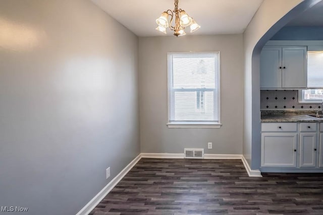 unfurnished dining area featuring visible vents, baseboards, arched walkways, and dark wood finished floors