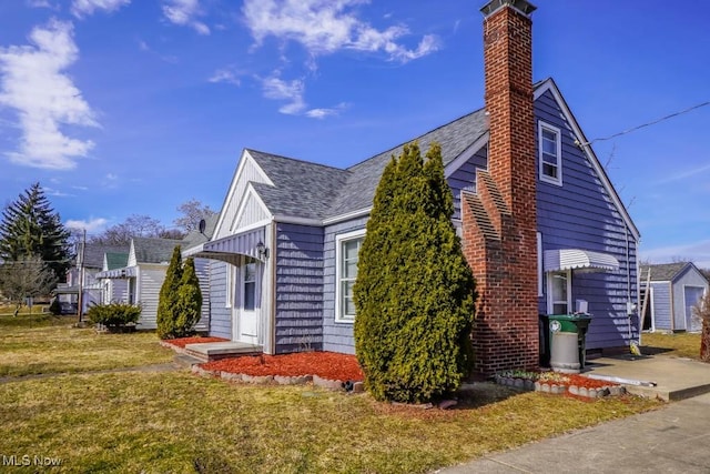 view of home's exterior featuring a shingled roof, a yard, and a chimney