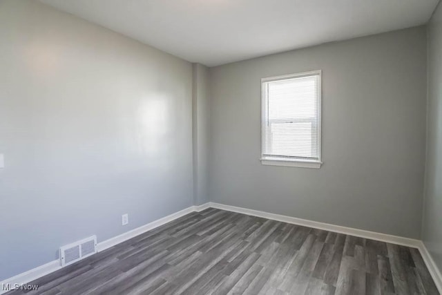 spare room with baseboards, visible vents, and dark wood-style flooring