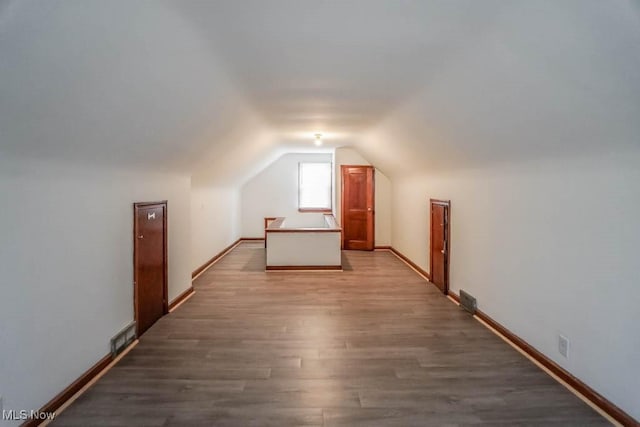 bonus room featuring visible vents, vaulted ceiling, baseboards, and wood finished floors