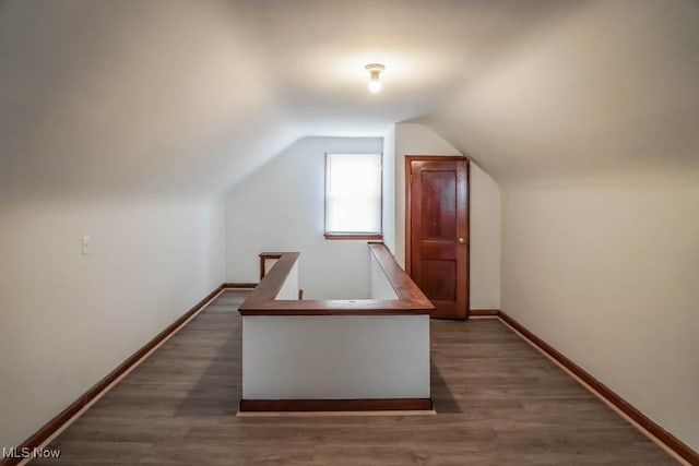 additional living space featuring lofted ceiling, dark wood finished floors, and baseboards