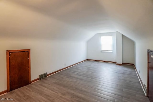 bonus room with baseboards, visible vents, vaulted ceiling, and wood finished floors