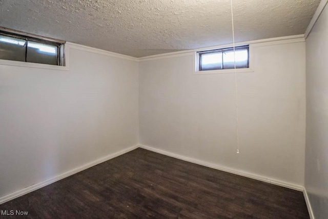 basement featuring a textured ceiling, dark wood finished floors, and baseboards