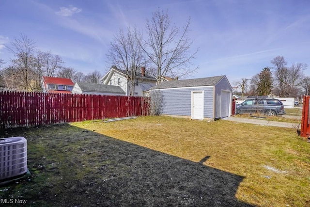 view of yard featuring a garage, fence, central AC, and an outbuilding