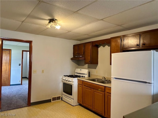 kitchen with a paneled ceiling, visible vents, a sink, white appliances, and under cabinet range hood