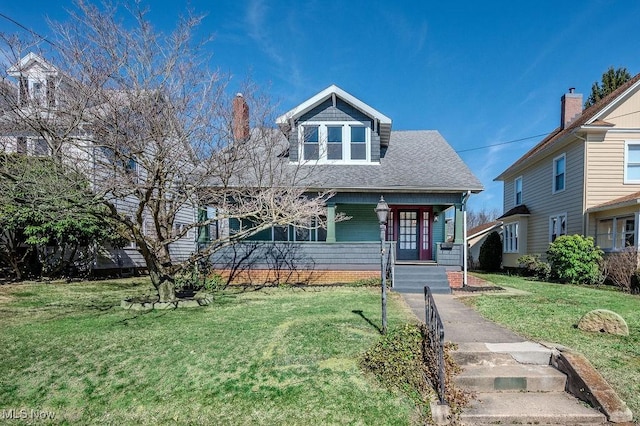 bungalow-style home with a shingled roof and a front lawn