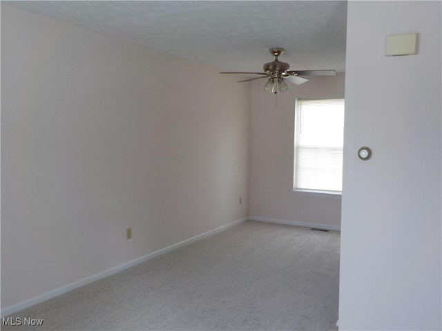 empty room with light carpet, ceiling fan, and baseboards