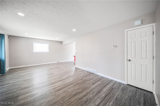 unfurnished room featuring baseboards, a textured ceiling, visible vents, and wood finished floors