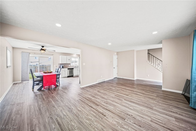 living area with baseboards, stairs, visible vents, and wood finished floors