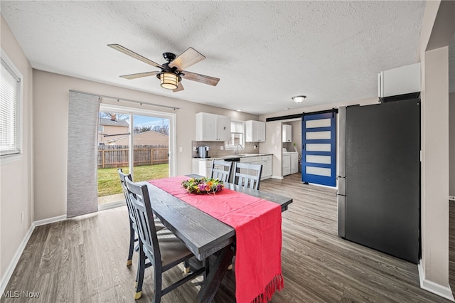 dining room featuring wood finished floors, ceiling fan, washer and clothes dryer, and a barn door