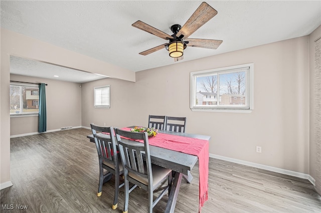 dining area featuring a ceiling fan, a textured ceiling, baseboards, and wood finished floors