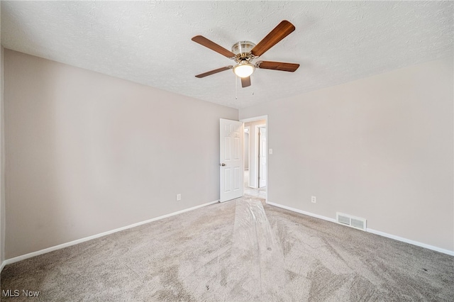 carpeted empty room featuring a textured ceiling, ceiling fan, visible vents, and baseboards