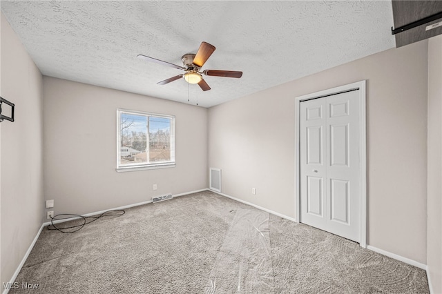 unfurnished bedroom with baseboards, visible vents, ceiling fan, a textured ceiling, and carpet floors