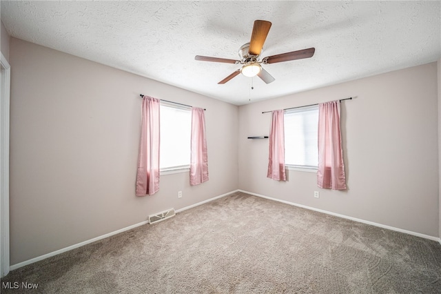 empty room with carpet, visible vents, and a textured ceiling