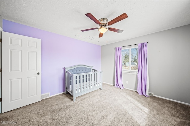 unfurnished bedroom with carpet, visible vents, a textured ceiling, and baseboards