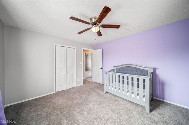 bedroom with carpet, a textured ceiling, baseboards, and a closet