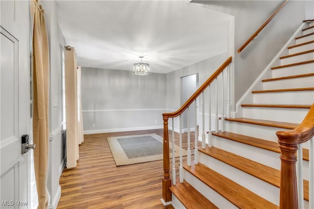 foyer with a chandelier, stairway, baseboards, and wood finished floors