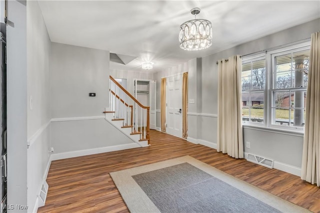 entryway with wood finished floors, visible vents, baseboards, and stairs