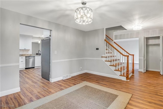 interior space featuring visible vents, an inviting chandelier, light wood-type flooring, baseboards, and stairs