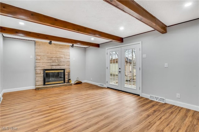 unfurnished living room featuring french doors, a fireplace, visible vents, light wood-type flooring, and baseboards