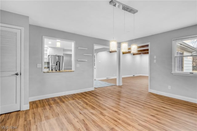 unfurnished dining area with baseboards and light wood-style floors