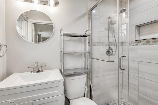 full bathroom with a stall shower, vanity, and toilet