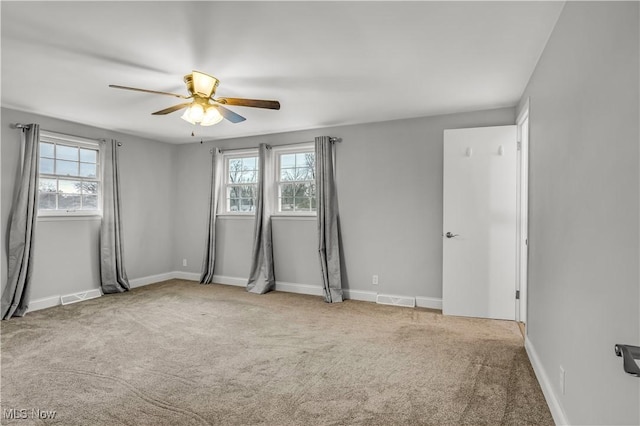 spare room featuring carpet floors, plenty of natural light, and visible vents