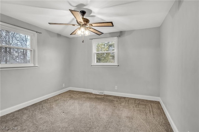 unfurnished room with carpet floors, plenty of natural light, visible vents, and baseboards