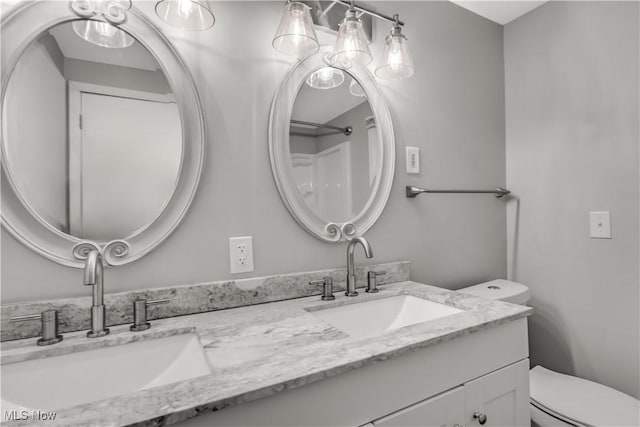 full bath with a sink, toilet, and double vanity