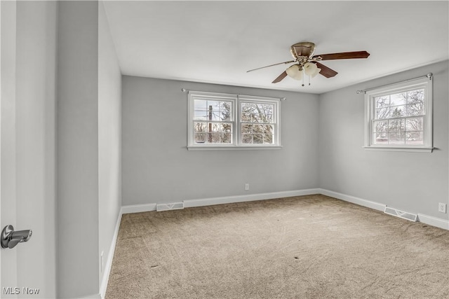 carpeted spare room with baseboards, visible vents, and a wealth of natural light