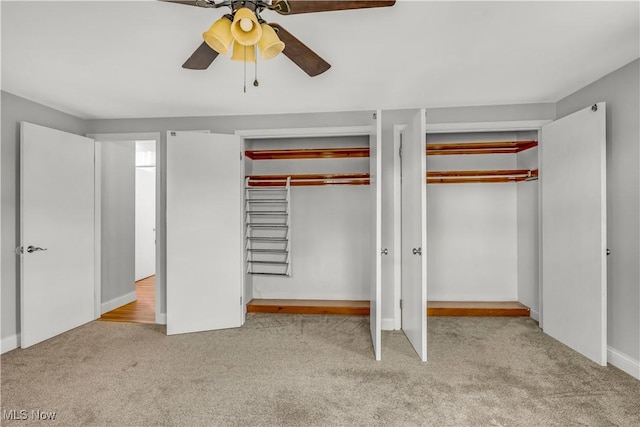 unfurnished bedroom featuring carpet, ceiling fan, and two closets