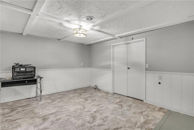 interior space with a wainscoted wall, a textured ceiling, and visible vents