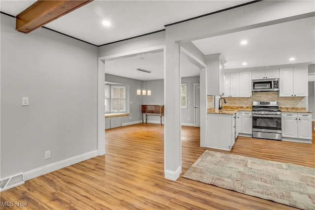 kitchen featuring stainless steel appliances, tasteful backsplash, visible vents, white cabinets, and light wood-type flooring