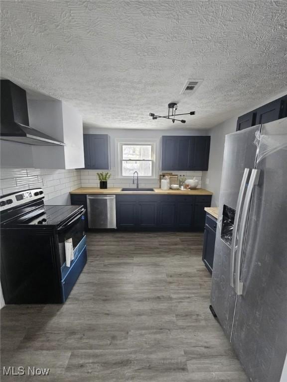 kitchen featuring a sink, visible vents, appliances with stainless steel finishes, wall chimney range hood, and light wood finished floors