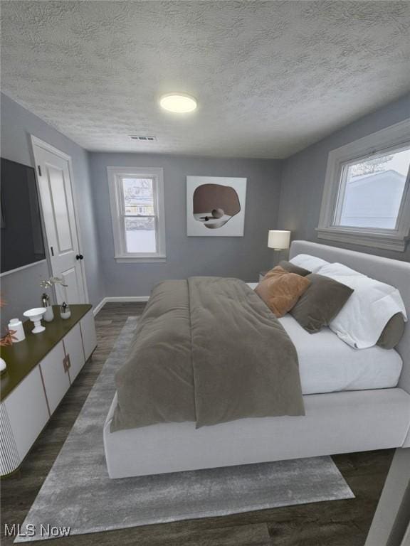 bedroom featuring a textured ceiling, visible vents, and dark wood-type flooring