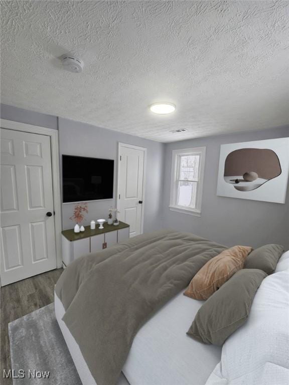 bedroom with a textured ceiling and wood finished floors