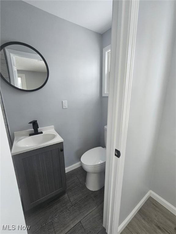 bathroom featuring baseboards, vanity, toilet, and wood finished floors