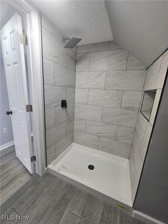 full bathroom featuring a stall shower, a textured ceiling, and wood finished floors