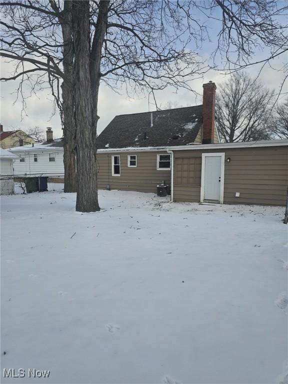 snow covered property with a chimney