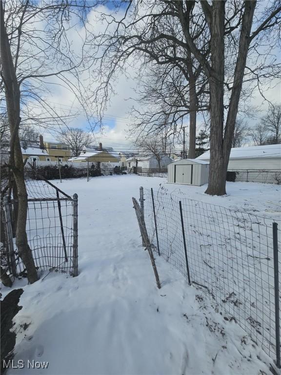 yard covered in snow with an outdoor structure, a storage shed, and fence